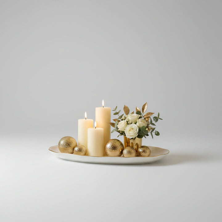 Decorative setup with candles, gold ornaments, and flowers on a marble surface.